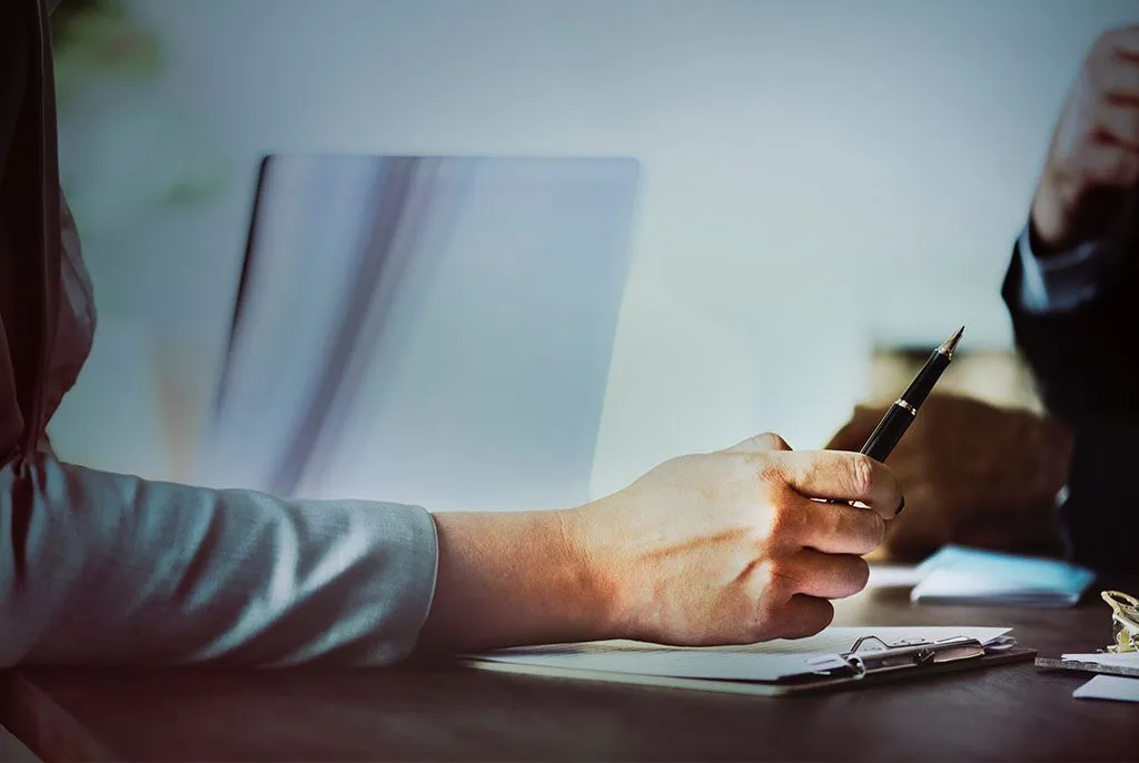 Signature de contrats et formulaires administratifs lors d'un rendez-vous.