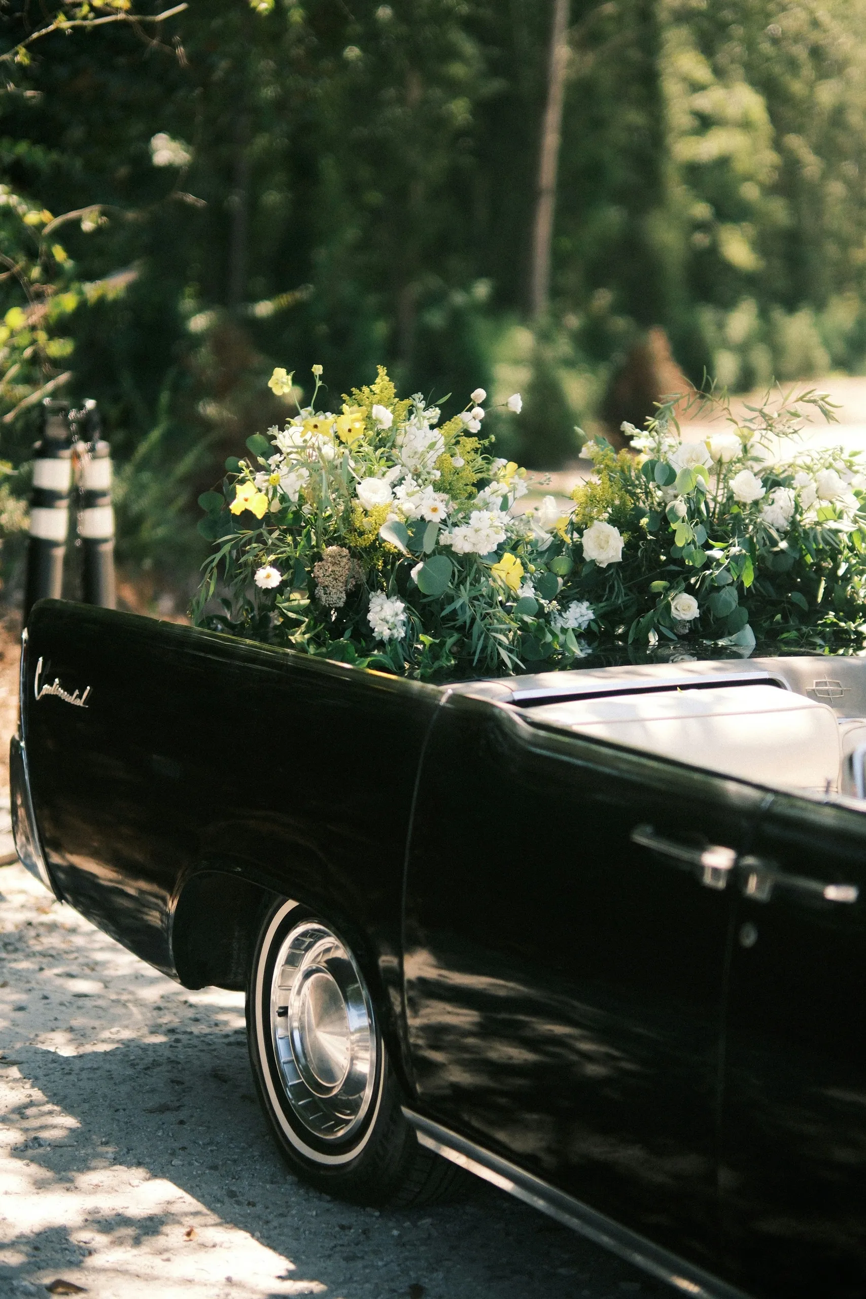 Arrière d'une voiture ancienne ornée de compositions de fleurs fraîches
